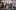 2024_New Views_Sweetness__ Rehearsed Reading_Emma Hare A group of ten people, consisting of six women and four men, are seated and standing on a stage. Two women in the front are holding a clapperboard with