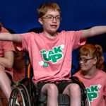 A young person in a wheelchair wearing a pink 