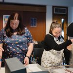 Four teachers stand looking through and handling National Theatre Archive materials.