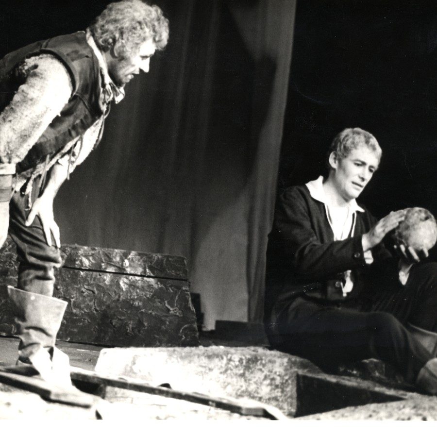 Hamlet-1963-FrankFinlay-PeterOToole-AngusMcBean-2000x1000 Actor Frank Finlay as Gravedigger and Peter O'Toole as Hamlet, holding a skull, on stage at the National Theatre, 1963