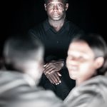 Kobna Holdbrook-Smith performing as Dr Toby Sealey in The Effect. He is wearing a black top and looking straight ahead.