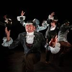 Border officers engaged in a dance routine, one officer facing the audience while mid-dance and holding a cigarette in his mout