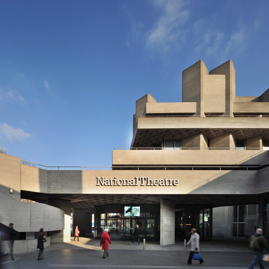 National Theatre entrance tall National Theatre building, main entrance exterior with name in raised lettering on the lower terrace balcony and people walking in the square in front.