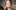 roasumnd-pike-headshot-2000x1250-photo-by-olivier-kingsley A woman with long, wavy blond hair wearing a black outfit gazes directly at the camera. The background is blurred, putting focus on her face. She has a calm expression and light makeup.