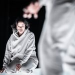 Taylor Russell as Connie in The Effect. She is wearing a white tracksuit and kneeling on the floor.