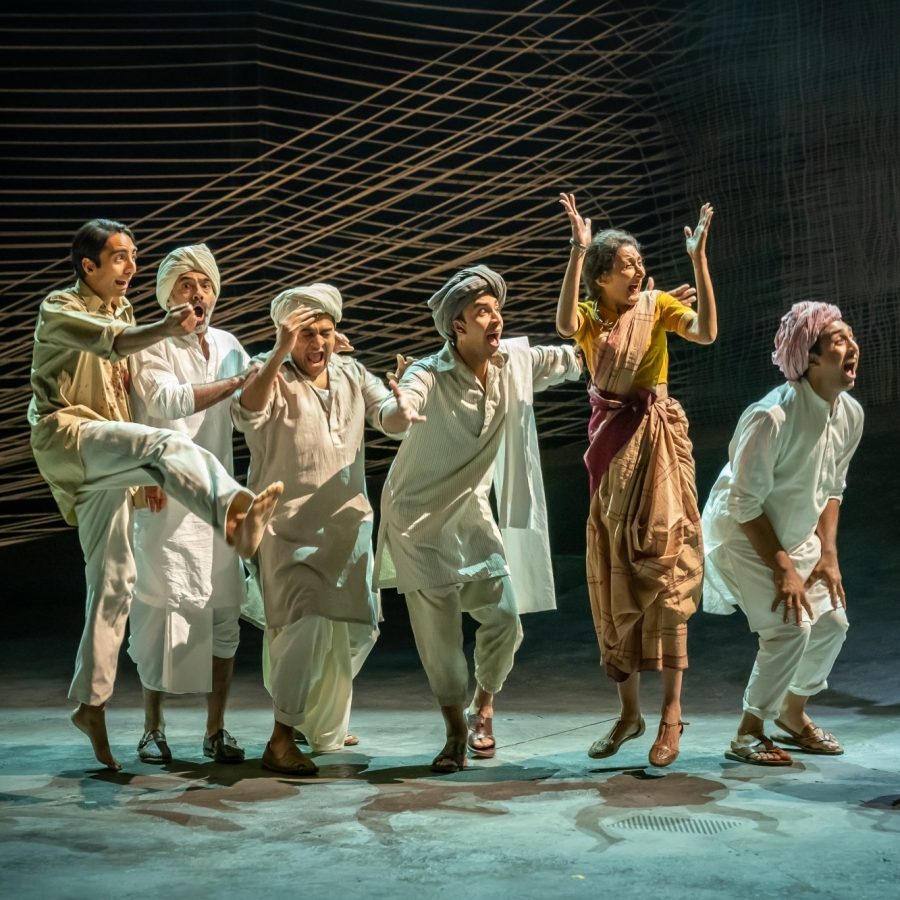 The Father and the Assassin company Seven people wearing loose cotton clothes, standing in a line. in celebratory poses.