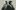The-Motive-and-the-Cue-Mark-Gatiss-Johnny-Flynn-2000x1250 Two men (Mark Gatiss and Johnny Flynn) stand back to back, with pensive expressions, each with one hand raised to their mouth.