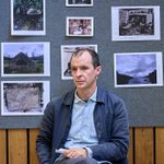 Tom Vaughan-Lawlor sitting in a chair wearing a light blue shirt and a dark blue jacket.